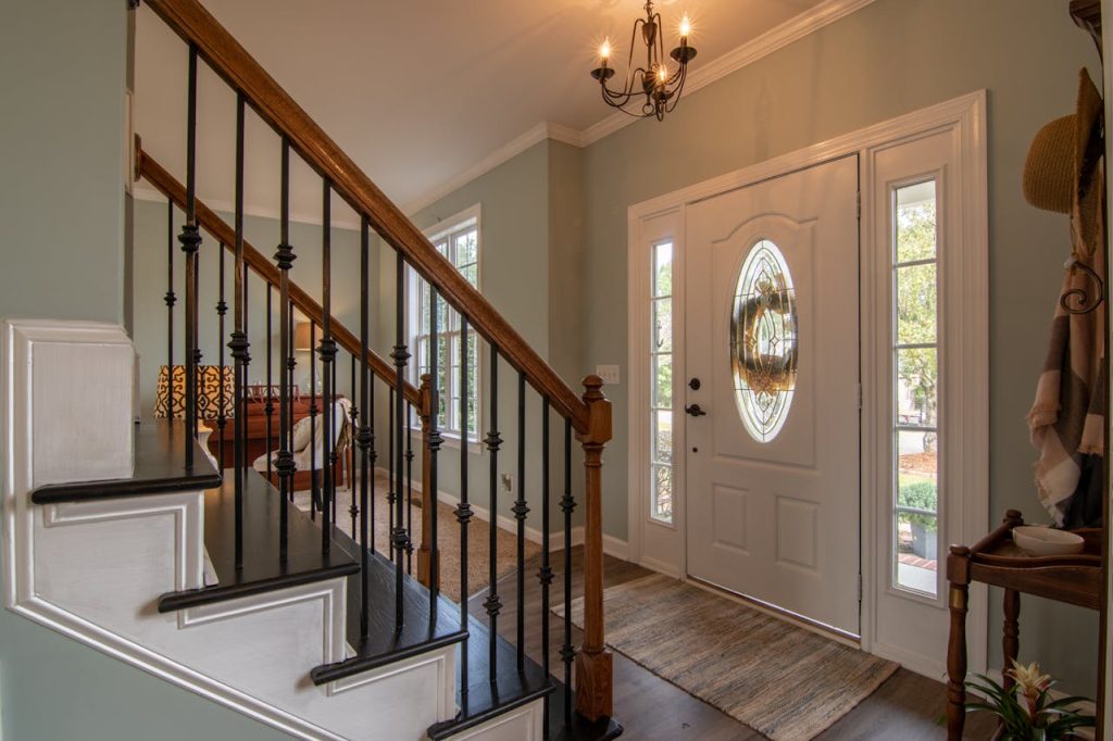 brown-wooden-staircase-with-brass-chandelier-3288103 Inviting modern hallway with staircase, chandelier, and natural daylight.